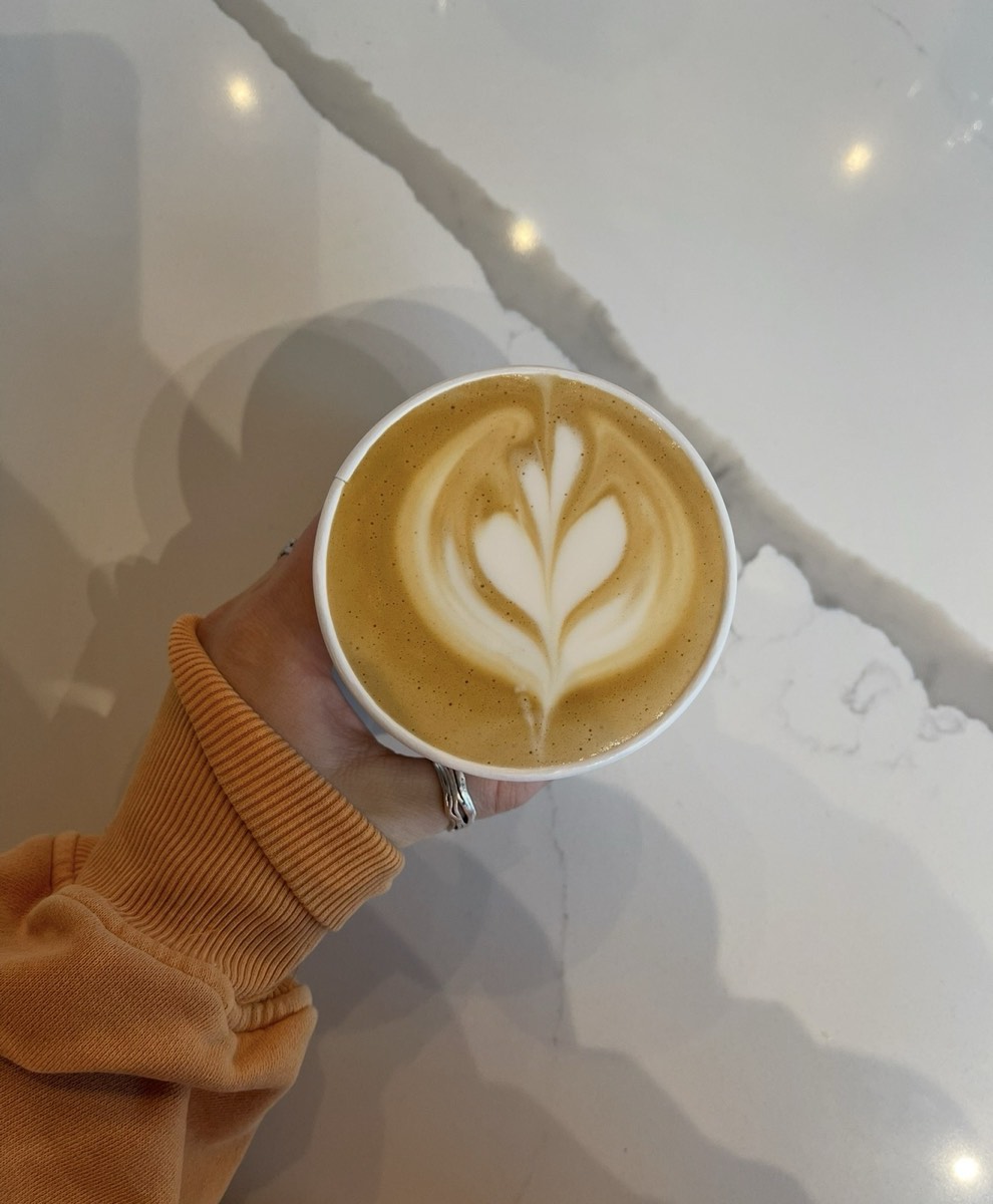A Coco's latte held over a marble counter